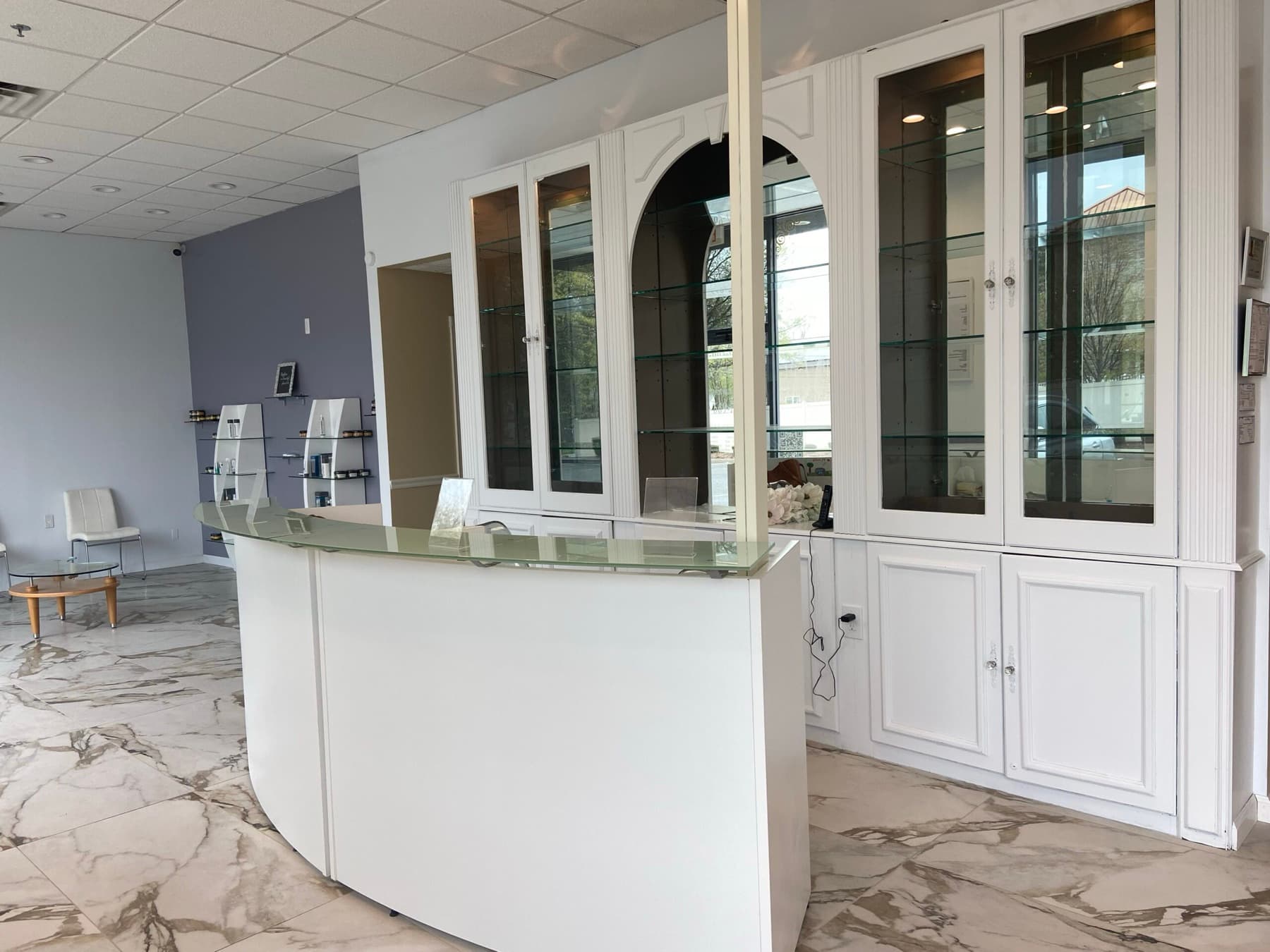 ReVibe reception with marble floor, curved white desk and arched display cabinetry